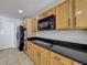 Well-lit kitchen boasts wood cabinetry, granite countertops, and modern black appliances at 1176 Liberty Hall Dr, Kissimmee, FL 34746
