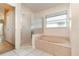 Bathroom featuring tiled floor, glass shower, soaking tub, and a window at 12213 Bohannon Blvd, Orlando, FL 32824