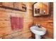 Rustic bathroom with wooden walls, pedestal sink, and medicine cabinet at 12213 Bohannon Blvd, Orlando, FL 32824