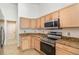 Corner view of the kitchen with stainless steel appliances, light wood cabinetry, and granite countertops at 12213 Bohannon Blvd, Orlando, FL 32824