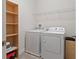 Bright laundry room features a washer, dryer, and shelving for storage at 14188 Walcott Ave, Orlando, FL 32827