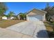 Home with a wide driveway, two-car garage, and nicely landscaped front yard with palm trees at 149 Southern Breeze Dr, Minneola, FL 34715