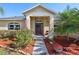 Inviting front entrance with colorful landscaping, mulched beds, and a welcoming wreath on the door at 149 Southern Breeze Dr, Minneola, FL 34715