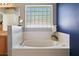 Soaking tub with decorative glass block window, complemented by a white tiled surround at 149 Southern Breeze Dr, Minneola, FL 34715