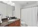 Well-lit bathroom features a vanity with dark countertops, a sink, a toilet, and a shower with a curtain at 150 E Robinson St # 1219, Orlando, FL 32801