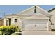 A two-car garage adds curb appeal with a carriage door, manicured bushes, and a charming exterior at 156 Eagleview Loop, Davenport, FL 33837