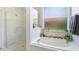 Bright bathroom featuring a soaking tub with decorative plants and a glass-enclosed shower at 1563 Song Sparrow Ct, Sanford, FL 32773