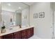 Bathroom with double sink vanity, large mirror, cherry wood cabinets, and access to walk-in shower and tub at 1563 Song Sparrow Ct, Sanford, FL 32773