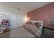 Bedroom featuring a daybed, neutral rug, and an accent wall painted in pink at 18907 Rawson St, Orlando, FL 32827