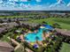 Aerial view of a community pool with vibrant umbrellas, surrounded by houses and expansive green space at 223 Silver Maple Rd, Groveland, FL 34736