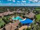 Aerial view of the community pool surrounded by palm trees, buildings, and colorful sunshades at 223 Silver Maple Rd, Groveland, FL 34736