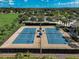 Aerial view of community tennis courts with well maintained blue courts and professional black fencing and lush landscaping at 223 Silver Maple Rd, Groveland, FL 34736
