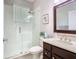 Bright bathroom features a glass enclosed shower with a window and dark wood vanity with a decorative framed mirror at 2332 Pond Cove Way, Apopka, FL 32712