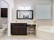 Bright bathroom has a jacuzzi tub and a vanity with a chair and mirror next to the toilet and a window at 2332 Pond Cove Way, Apopka, FL 32712