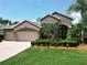 Beautifully landscaped home with a three-car garage, mature trees, and lush green lawn at 2332 Pond Cove Way, Apopka, FL 32712