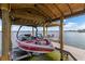 Covered boat lift showing a red and white boat, with lake and seating in the background at 2501 Trentwood Blvd, Belle Isle, FL 32812