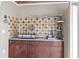 Outdoor kitchen featuring dark cabinets, counter space, a cooktop, and a tiled backsplash at 2501 Trentwood Blvd, Belle Isle, FL 32812