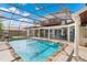 Gorgeous in-ground pool with screened enclosure, stone surround, and a beautiful home exterior backdrop at 2501 Trentwood Blvd, Belle Isle, FL 32812