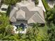 Stunning aerial view showcases a tile-roofed house with a uniquely shaped pool surrounded by lush, mature landscaping at 25519 Hawks Run Ln, Sorrento, FL 32776