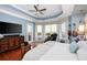 Large primary bedroom with tray ceiling, media console, and a relaxing massage chair by the bay windows at 25519 Hawks Run Ln, Sorrento, FL 32776