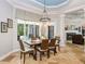 Dining room with a modern chandelier, woven chairs, and a view into the living room and covered outdoor space at 25519 Hawks Run Ln, Sorrento, FL 32776