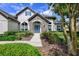 Charming home featuring a stone entrance, blue door, lush landscaping and manicured lawn at 25519 Hawks Run Ln, Sorrento, FL 32776