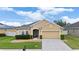 Inviting one-story home featuring a tan exterior, green lawn, and a well-manicured front yard at 3505 Rhapsody St, St Cloud, FL 34772