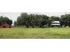 Charming two-story farmhouse with a red barn, surrounded by lush greenery and mature trees at 3650 Lake Tohopekaliga Rd, St Cloud, FL 34772