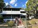 Exterior view of a charming two-story home featuring a porch, mature trees, and a fenced yard at 3650 Lake Tohopekaliga Rd, St Cloud, FL 34772