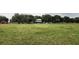 Expansive grass lot with a distant view of home, barn and lush trees at 3650 Lake Tohopekaliga Rd, St Cloud, FL 34772