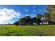 Expansive green field with mature trees and blue sky surrounding the property at 3650 Lake Tohopekaliga Rd, St Cloud, FL 34772