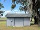 Gray outbuilding with a garage door on a grassy lot with a shade tree at 3650 Lake Tohopekaliga Rd, St Cloud, FL 34772