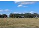 Large open field on the property with trees and buildings in the distance at 3650 Lake Tohopekaliga Rd, St Cloud, FL 34772