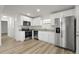Modern kitchen boasts stainless steel appliances, granite counters, white cabinets and wood-look floors for a sleek design at 4510 Douglas St, Sanford, FL 32771