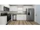 A view of the kitchen showcasing stainless steel appliances and wood grain flooring at 4510 Douglas St, Sanford, FL 32771