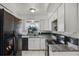 Well lit kitchen featuring granite countertops, white cabinets, and black appliances at 4908 Keith Pl, Orlando, FL 32808