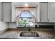 Close-up of kitchen sink featuring granite countertops and a backyard view through the window at 4908 Keith Pl, Orlando, FL 32808