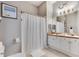 Well-lit bathroom with dual sinks, white cabinets, and shower tub with curtain at 505 Terrace Ridge Cir # 505, Davenport, FL 33896