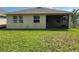 View of the home's back exterior, with a screened in porch and a spacious lawn at 5550 Bakewell Pl, St Cloud, FL 34771
