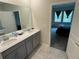 Bathroom with dual sinks, gray cabinets, and an ensuite to the main bedroom at 5550 Bakewell Pl, St Cloud, FL 34771