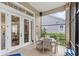 View of the screened in patio with wooden table and four chairs, adjacent to large glass paneled doors at 6037 Caymus Loop, Windermere, FL 34786