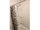 A close-up of a shower-tub with a white surround and gray and white patterned curtain at 7900 S Orange Blossom Trl # 2025, Orlando, FL 32809