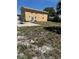 Backyard view of a home, featuring a patio and an unkept grassy yard at 8 E Summit St, Apopka, FL 32712