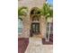 Inviting front entry featuring brick archway, double doors, and lush tropical landscaping at 8453 Firefox Cv, Orlando, FL 32835