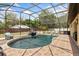 Sparkling pool inside screened enclosure with rock waterfall feature and chairs for lounging at 8453 Firefox Cv, Orlando, FL 32835