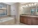 Bathroom features a soaking tub, granite countertop vanity, and a window at 8925 Azalea Sands Ln # 602, Davenport, FL 33896