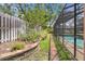 Landscaped backyard with greenery, brick and stone edging and a view of the screened-in pool at 105 Valley Ct, Longwood, FL 32779