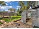 A greenhouse structure in a grassy backyard with a stepping stone path and a partial view of a screened-in pool at 105 Valley Ct, Longwood, FL 32779
