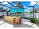 Spacious screened patio features an outdoor kitchen, bar seating, and bright umbrellas at 11718 Fitzgerald Butler Rd, Orlando, FL 32836