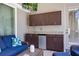 Outdoor kitchen featuring dark cabinets, granite countertops, a mini fridge and a mounted TV at 128 Hallstrom Ct, Debary, FL 32713